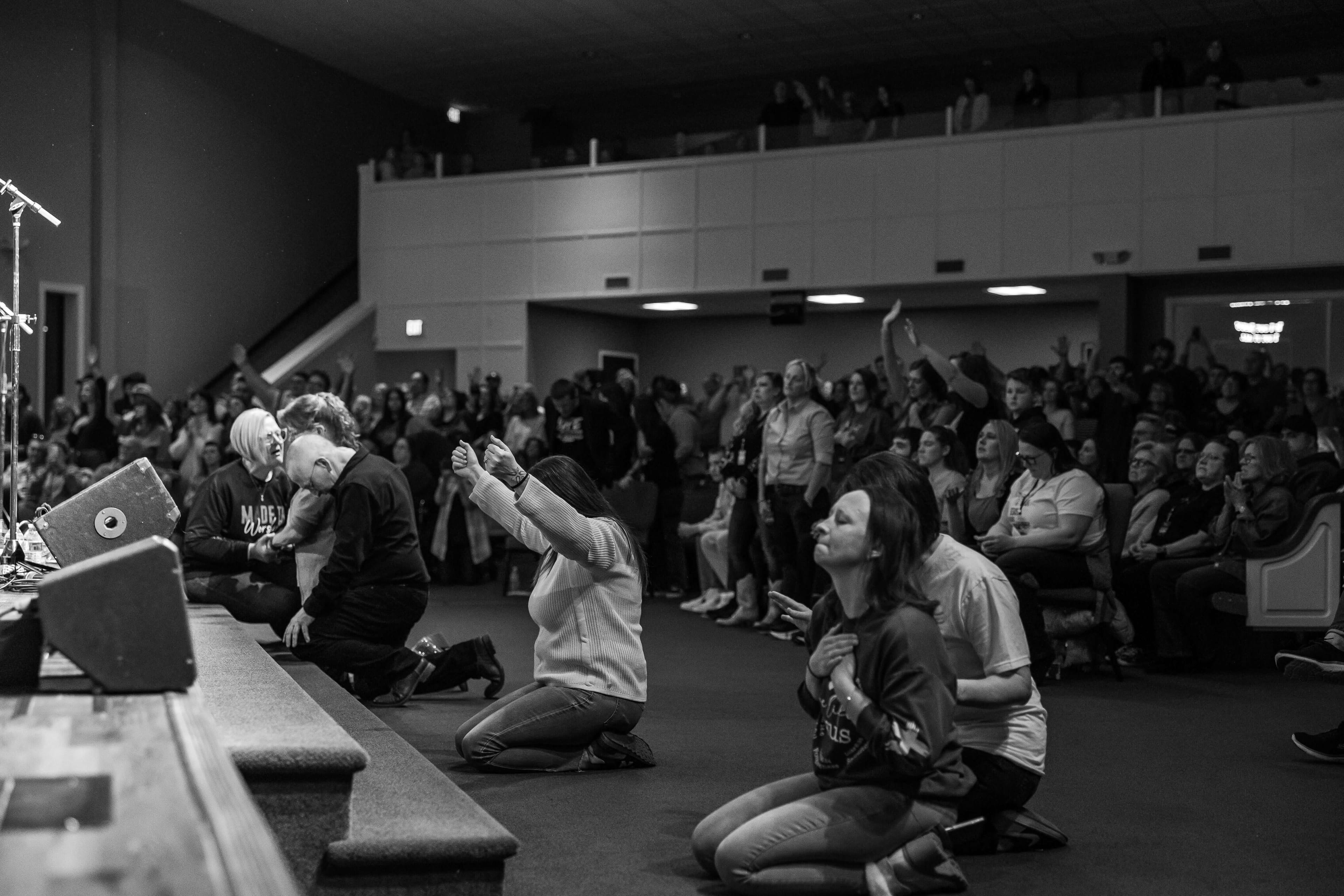 People kneeling in prayer and worship at a faith-based recovery event